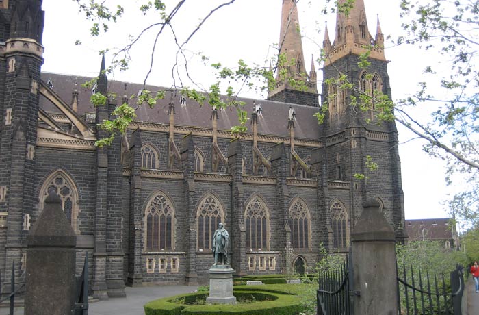 Costado izquierdo de la Catedral de San Patricio y estatua del irlandés Daniel O'Connell qué ver en Melbourne