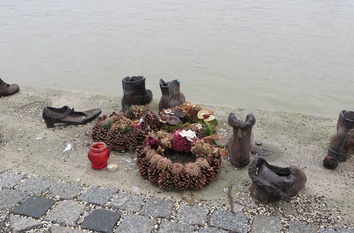 Flores y velas junto a los zapatos del Danubio