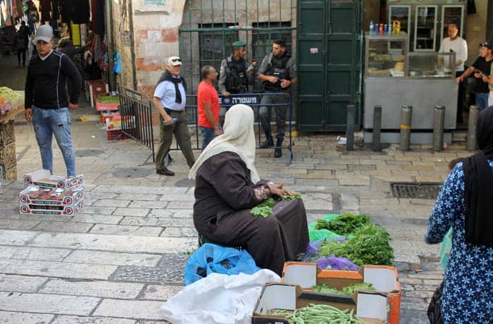 Una mujer musulmana vende verdura junto a un puesto policial israelí en el barrio musulmán qué ver en Jerusalén